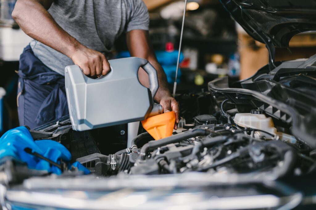 Closeup Garage Mechanic professional working car auto service engine oil filling up.