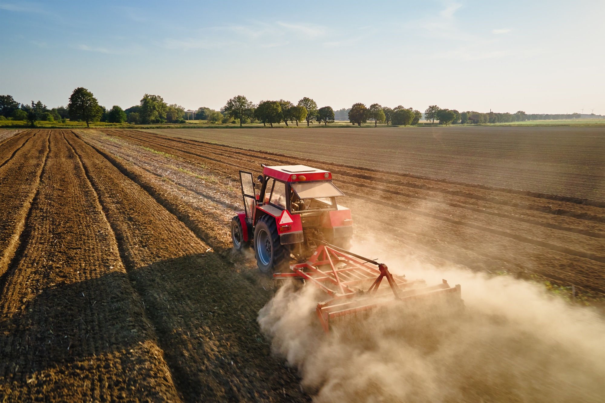 Tractor working in agricultural field, cultivating and plowing dry soil