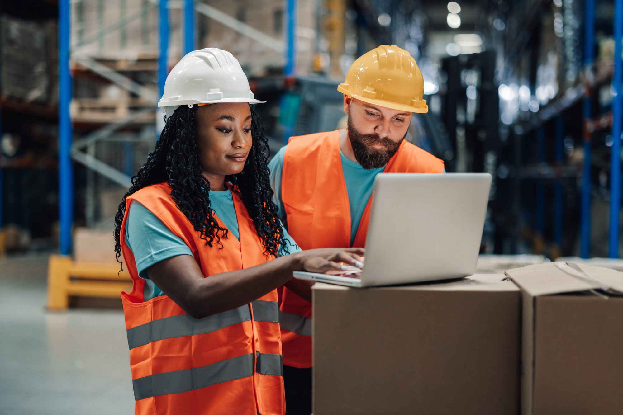 Warehouse workers using laptop checking inventory in logistics center